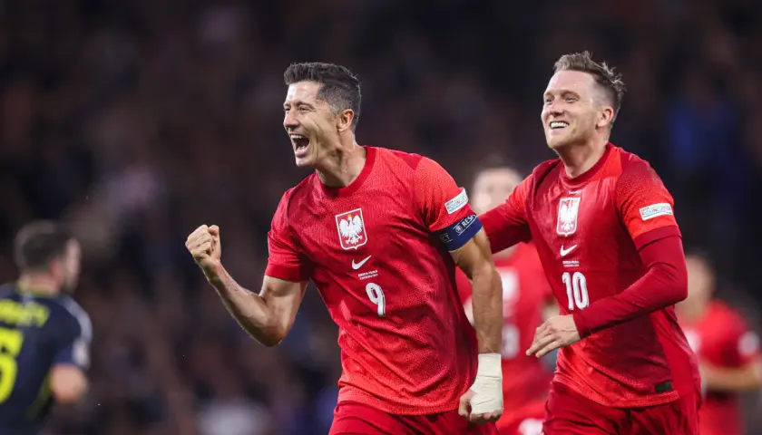 Dwóch radośnie świętujących byli piłkarze reprezentacji Polski w czerwonych strojach. Lewandowski z numerem 9 i Zieliński z numerem 10.