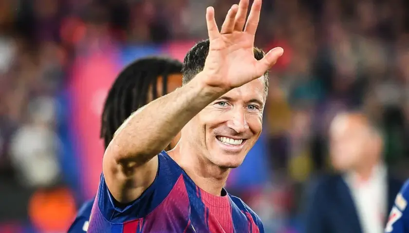 Robert Lewandowski wita kibiców, uśmiechając się szeroko. Wszyscy zastanawiają się, o co chodzi z Lewandowskim i jego nowym klubem.