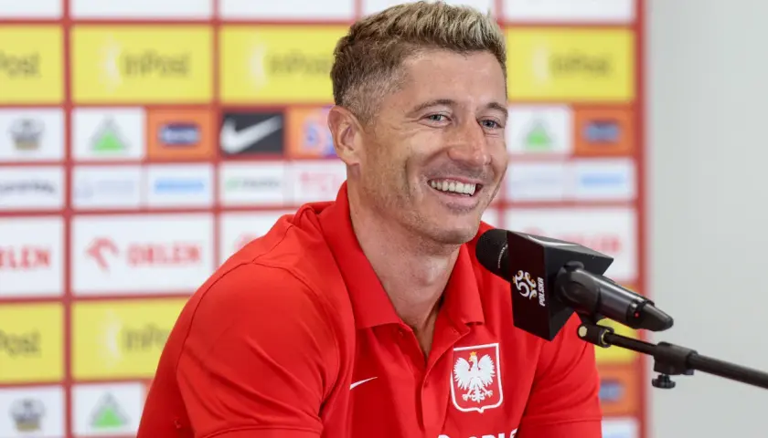 Uśmiechnięty Robert Lewandowski w czerwonej koszulce reprezentacji Polski, przed mikrofonem. Ile języków zna Robert Lewandowski?