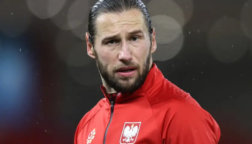 Piłkarz w czerwonej bluzie z orłem na piersi, w deszczu. Krychowiak gdzie gra? Na boisku, w barwach narodowych.