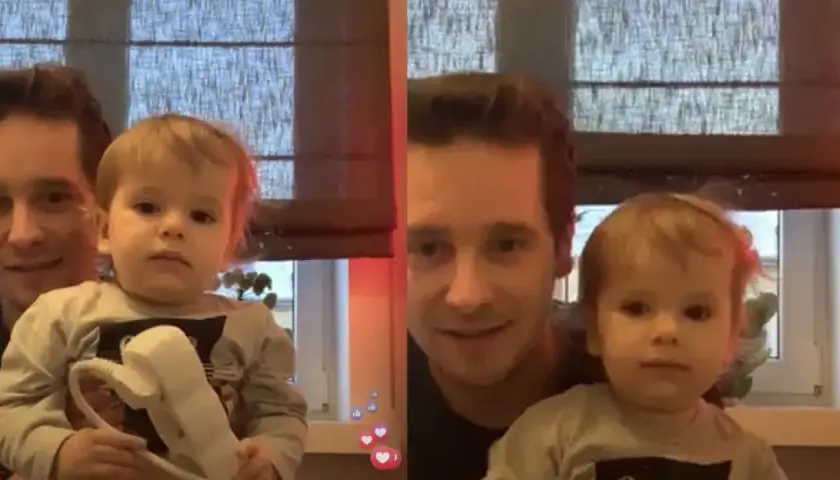 Nicola Zalewski tata z synkiem. Uśmiechnięty ojciec trzyma dziecko, które bawi się słuchawką telefonu.