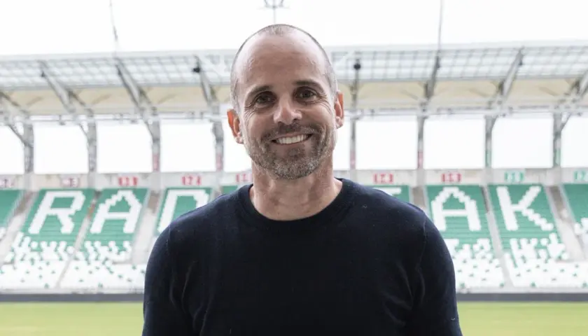 Uśmiechnięty trener Radomiaka na tle stadionu.