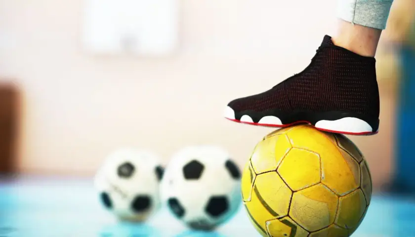 Stopa na żółtej piłce, w tle dwie białe. To może być początek przygody z futsalem.