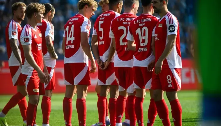 Piłkarze Union Berlin w czerwonych strojach z białymi detalami, w skupieniu przed meczem z Borussią.