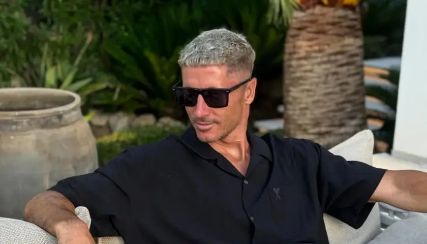 Robert Lewandowski w czarnej koszuli i okularach przeciwsłonecznych, relaksujący się w ogrodzie. Jego majątek robi wrażenie.