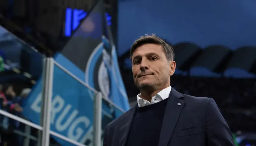 Trener piłkarzy z Mediolanu, z flagami Interu w tle, gotowy do meczu.