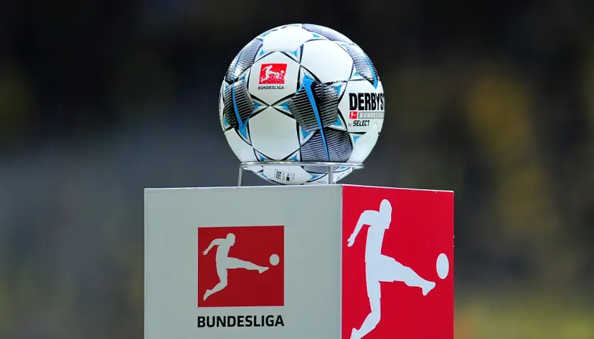 Piłka do gry w piłkę nożną na tle logotypów 2. Bundesliga. Zawodnicy tej ligi już wkrótce rozpoczną emocjonujące mecze.