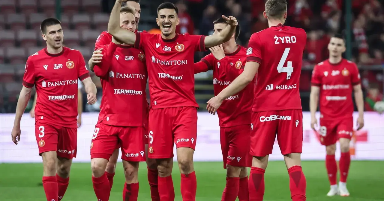Piłkarze Widzewa Łódź w czerwonych strojach świętują na boisku.