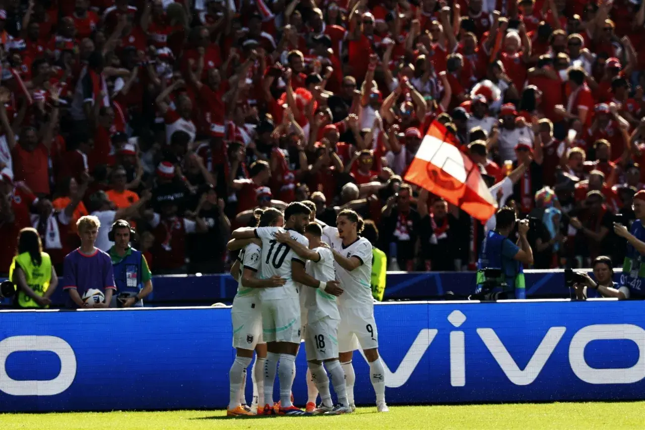 Piłkarze Austrii świętują zwycięstwo nad Holandią. Tłum kibiców na trybunach w biało-czerwonych barwach.
