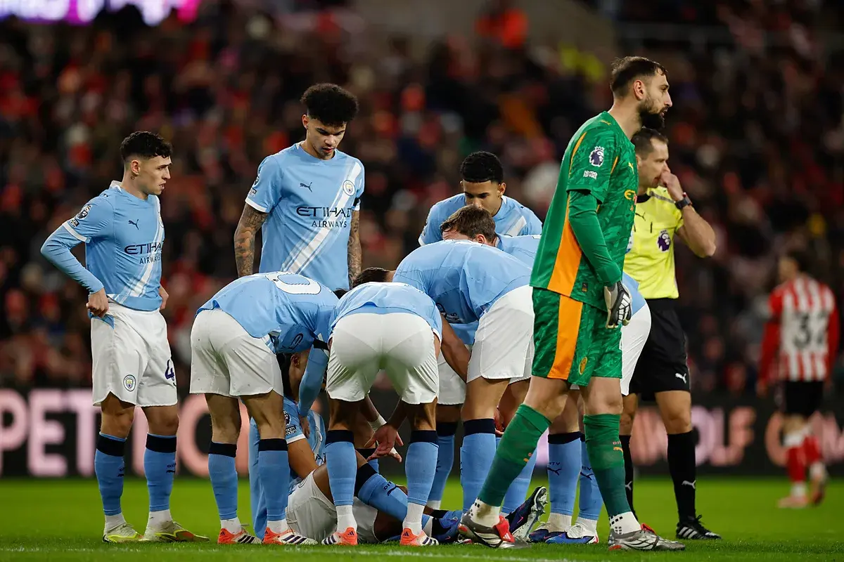 Piłkarze Manchesteru City w jasnoniebieskich strojach zbierają się w kółku na boisku. Skład drużyny w akcji.