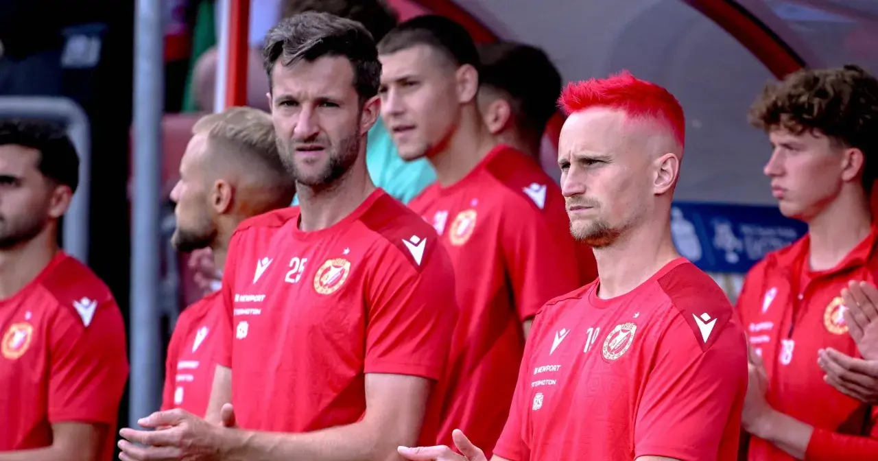 Piłkarze Widzewa Łódź w czerwonych koszulkach, jeden z nich ma jaskrawo-czerwone włosy.