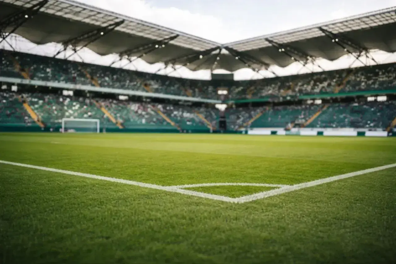 Pusta trybuna stadionu, gotowa na mecz rewanżowy. Zielona murawa i białe linie boiska czekają na emocje.