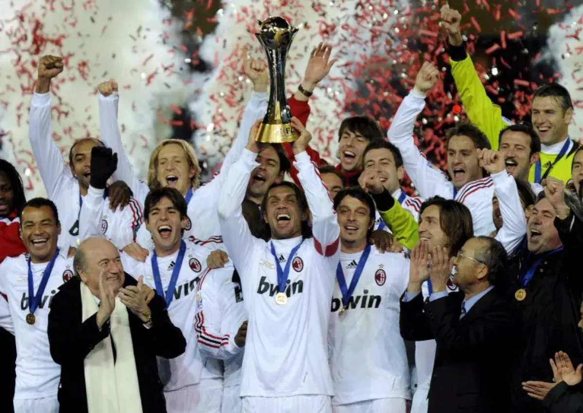 Piłkarze AC Milan świętują z pucharem, w tle konfetti i dym.