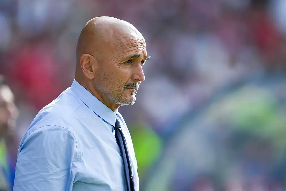 Łysy mężczyzna z wąsami, ubrany w błękitną koszulę i krawat, w skupieniu obserwuje boisko. To trener Juventusu.