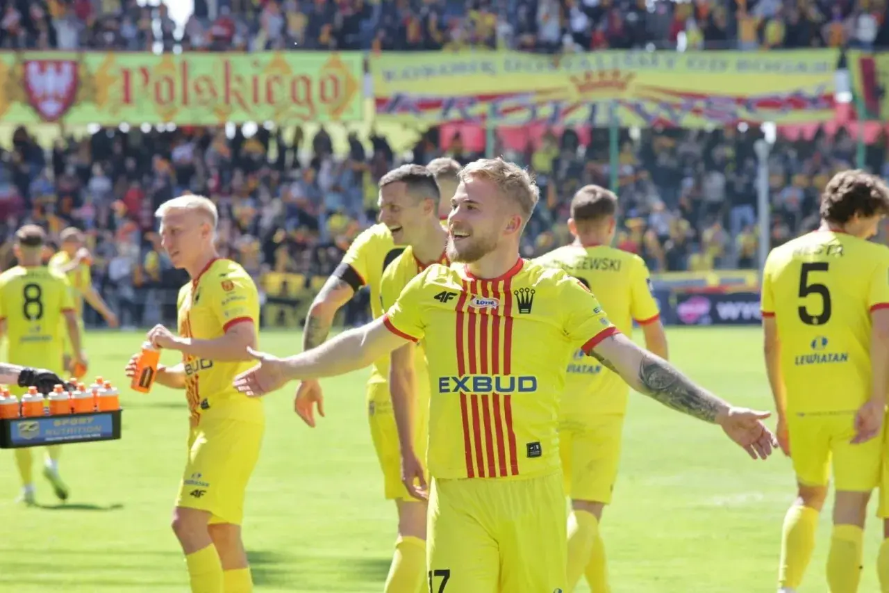 Piłkarze Korony Kielce w żółtych strojach świętują po meczu z Jagiellonią Białystok. Radość na twarzach zawodników.
