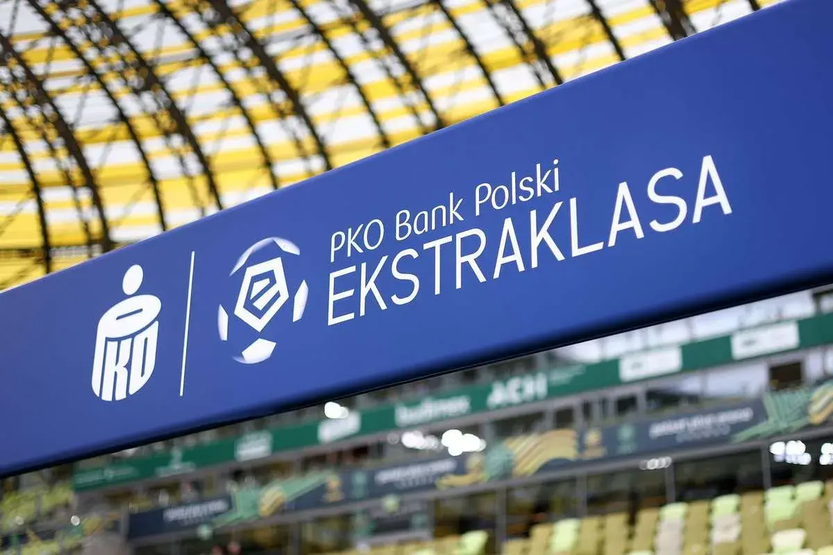 Niebieski baner z logo PKO Bank Polski Ekstraklasa na tle stadionu.