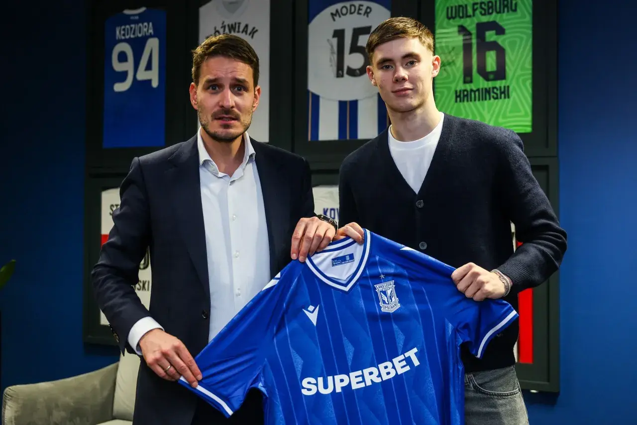 Dwóch mężczyzn prezentuje niebieską koszulkę Lecha Poznań. To kolejny z ekscytujących lech poznan transfery.