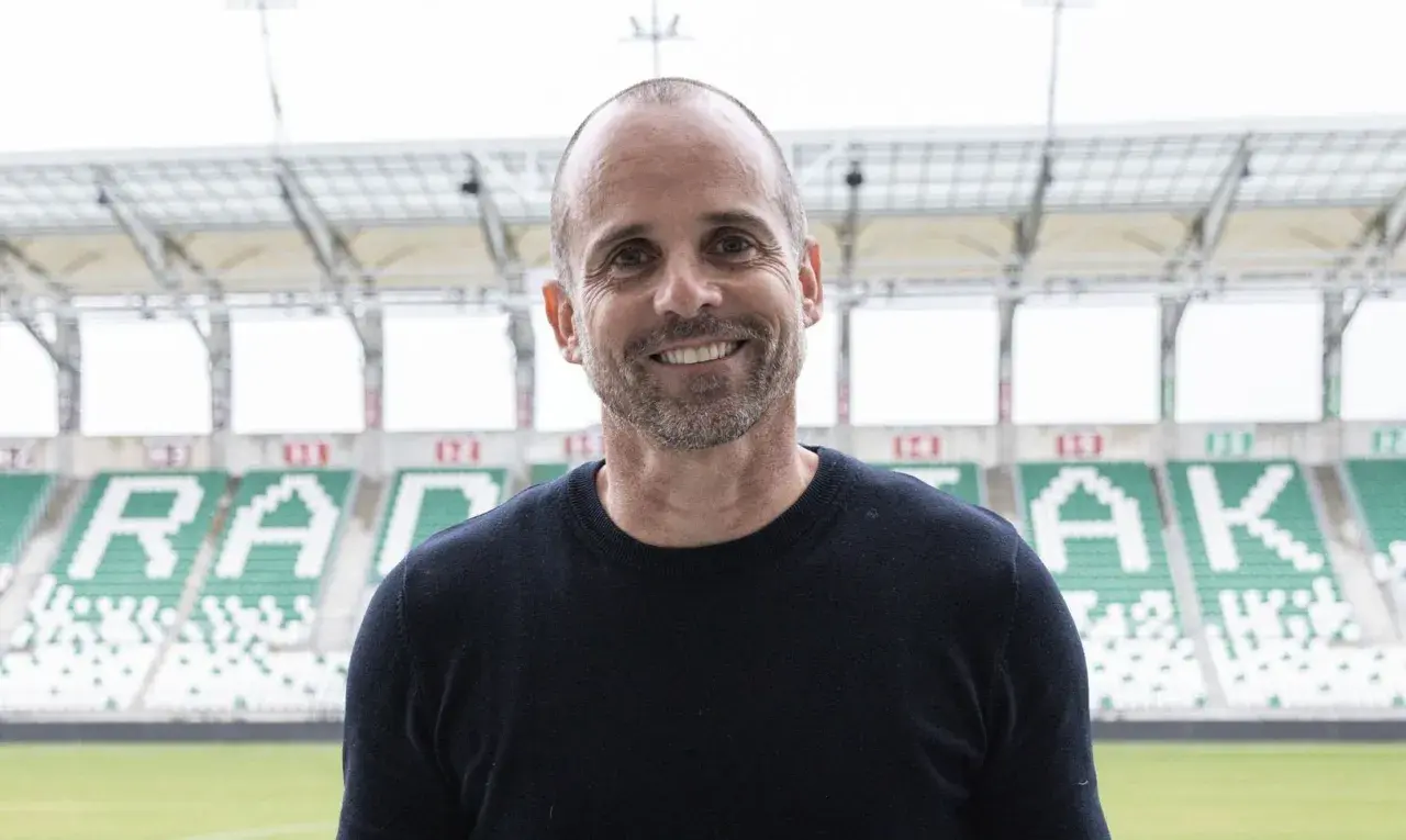 Uśmiechnięty trener Radomiaka na tle stadionu.