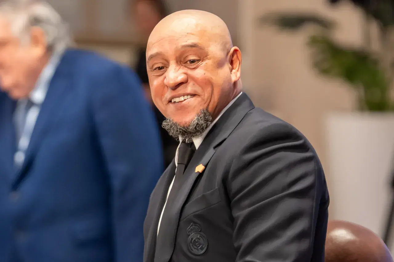 Roberto Carlos żyje i uśmiecha się szeroko, ubrany w elegancki garnitur z herbem Realu Madryt.