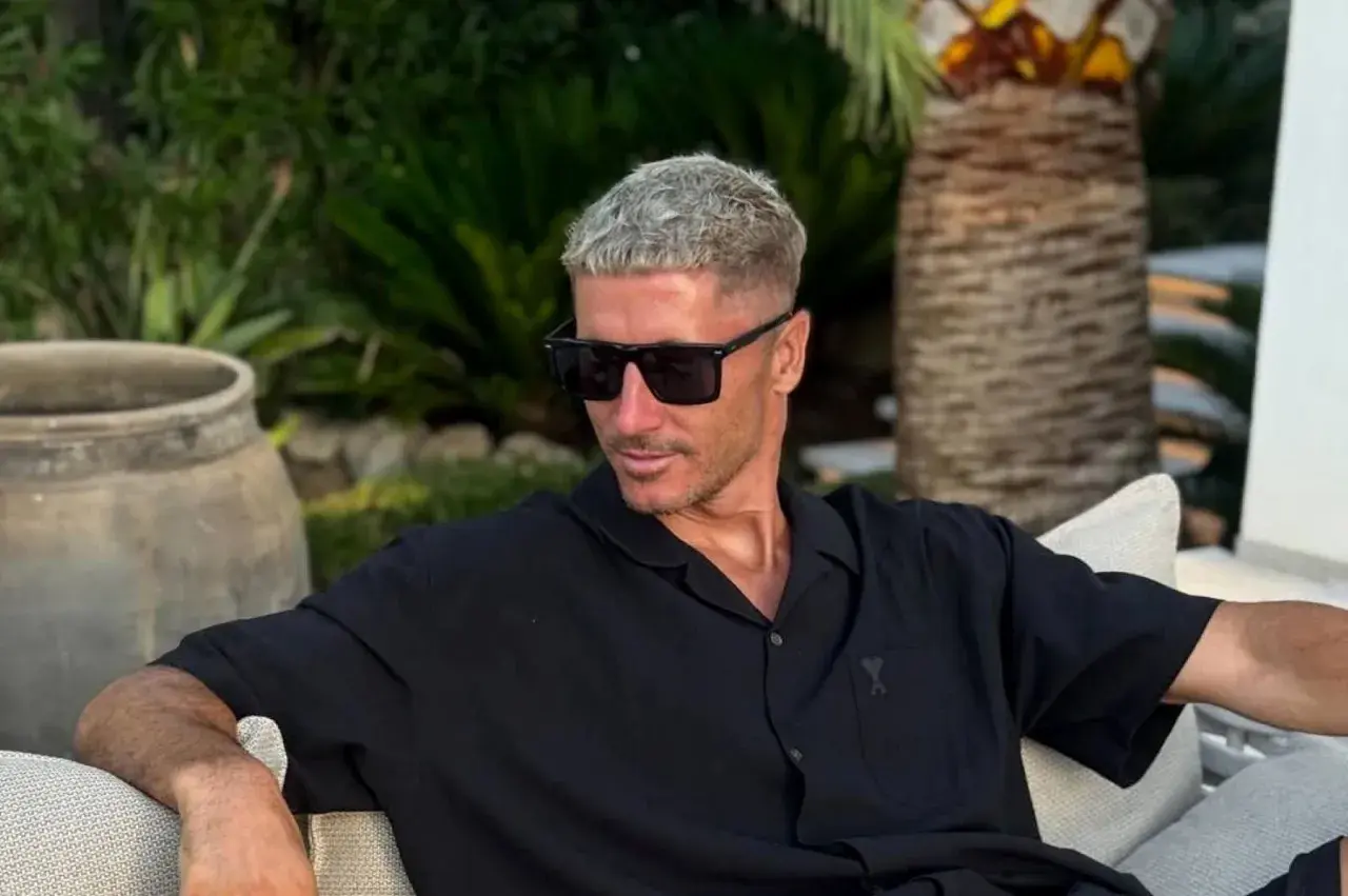 Robert Lewandowski w czarnej koszuli i okularach przeciwsłonecznych, relaksujący się w ogrodzie. Jego majątek robi wrażenie.