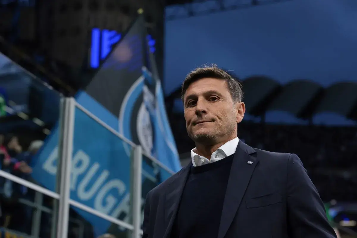Trener piłkarzy z Mediolanu, z flagami Interu w tle, gotowy do meczu.