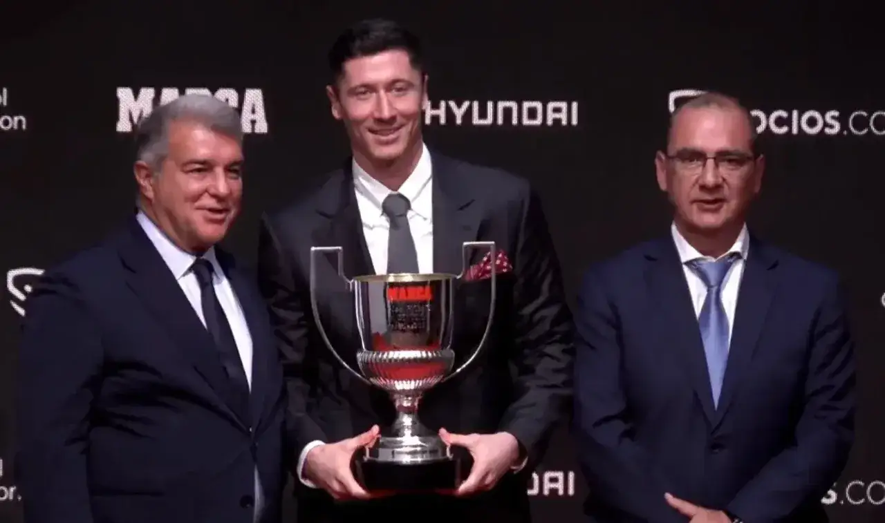 Robert Lewandowski z pucharem Pichichi, obok niego stoją Laporta i inny mężczyzna.