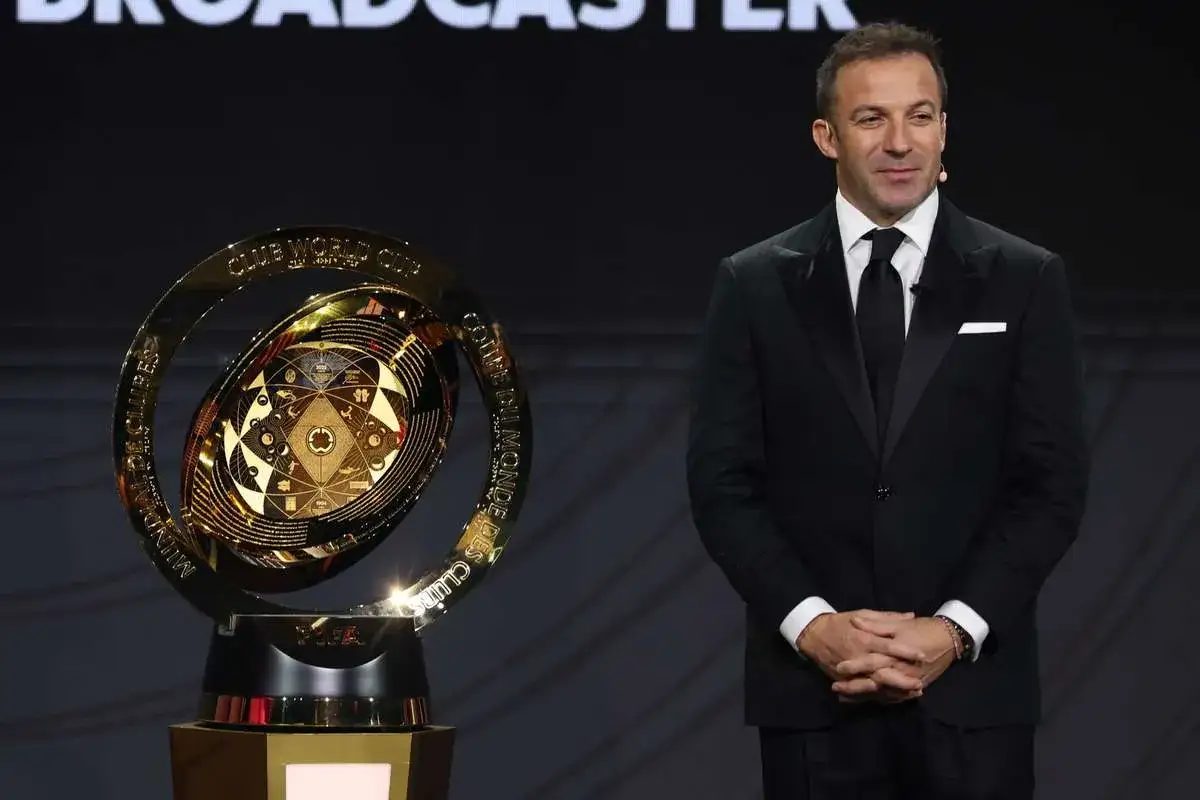 Złoty puchar Klubowych Mistrzostw Świata FIFA, obok elegancko ubranego mężczyzny.