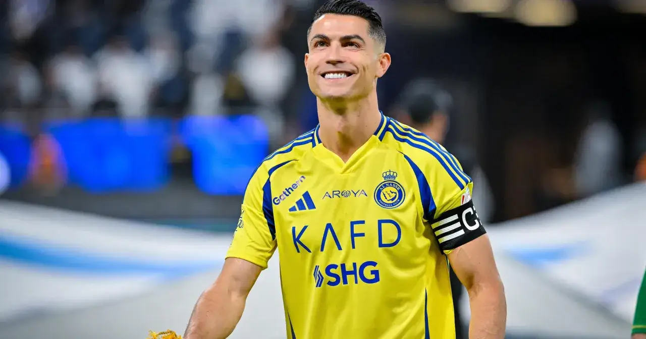 Uśmiechnięty Cristiano Ronaldo w żółtej koszulce Al Nassr. W jakich klubach grał Ronaldo? To pytanie nurtuje fanów na całym świecie.