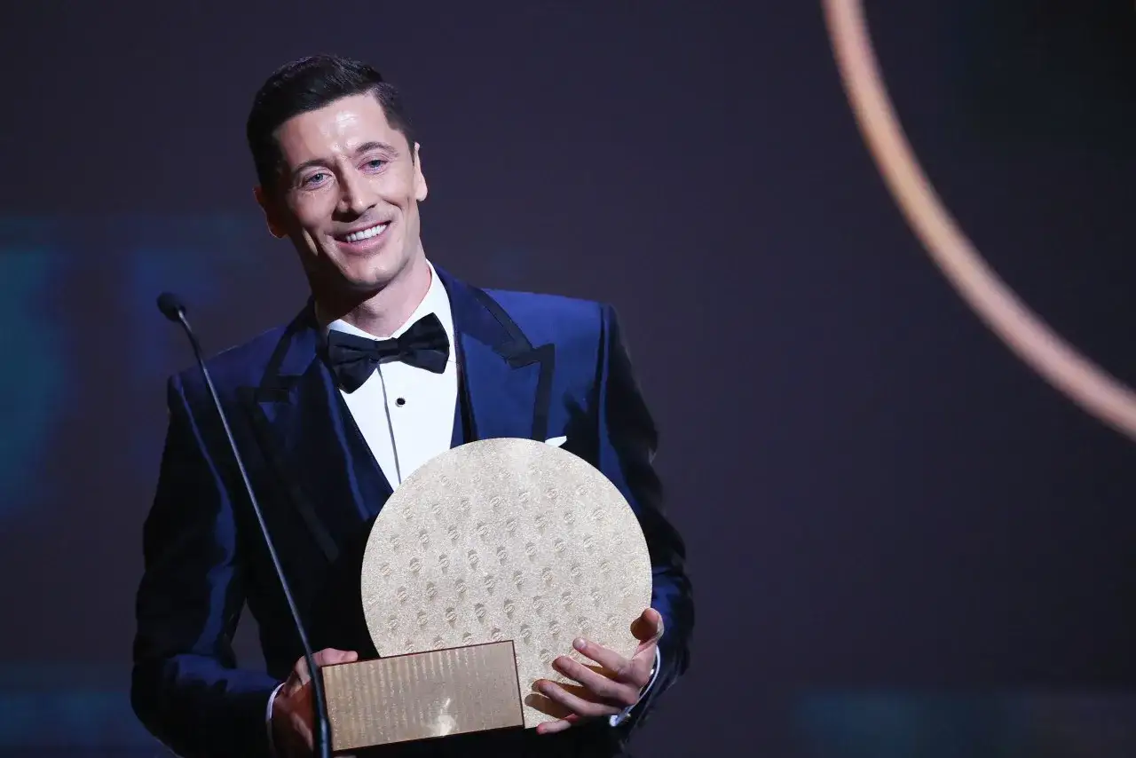 Robert Lewandowski z dumą prezentuje nagrodę, która przypomina Złotą Piłkę.
