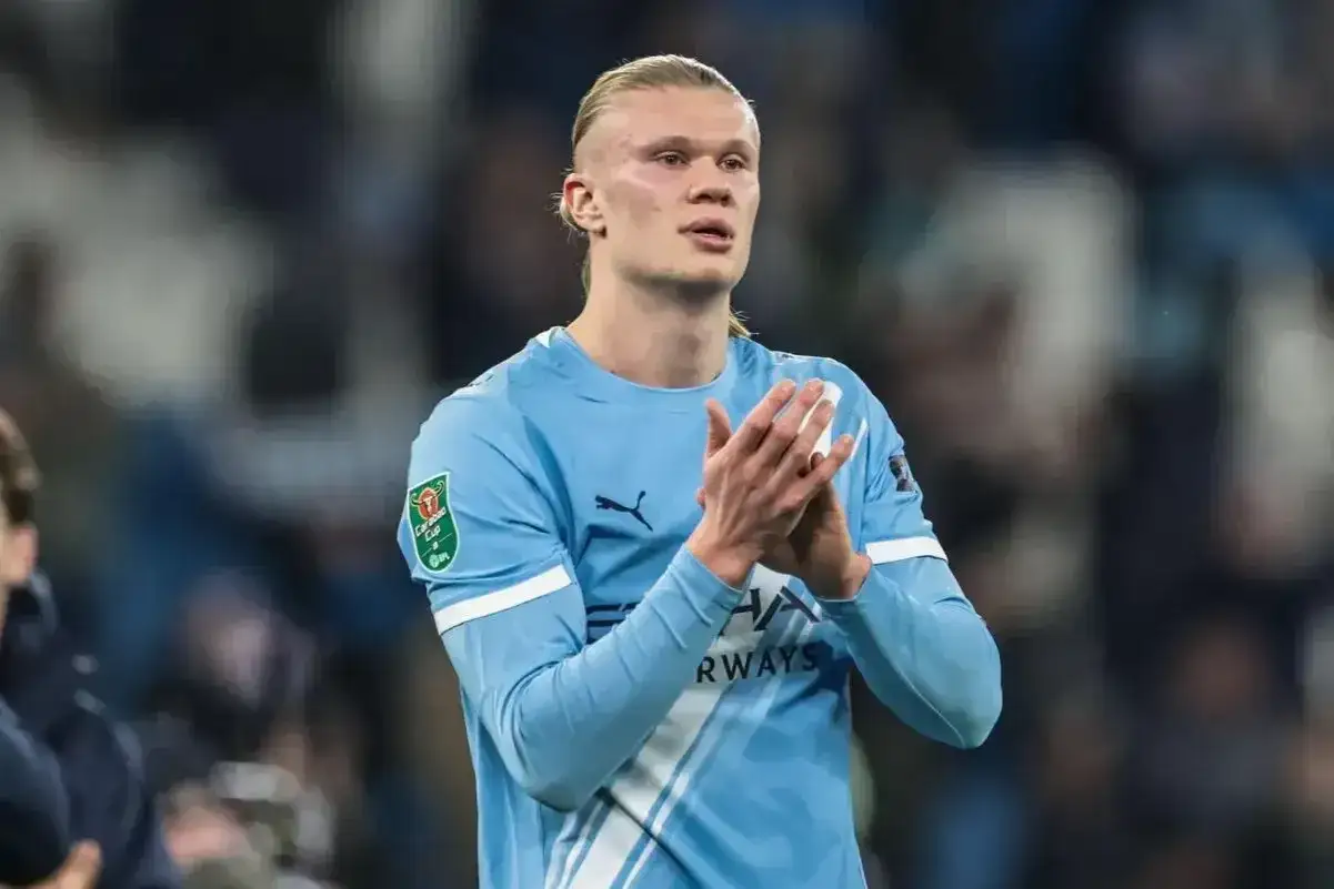 Erling Haaland, król strzelców, w błękitnej koszulce Manchesteru City, klaszcze na boisku.