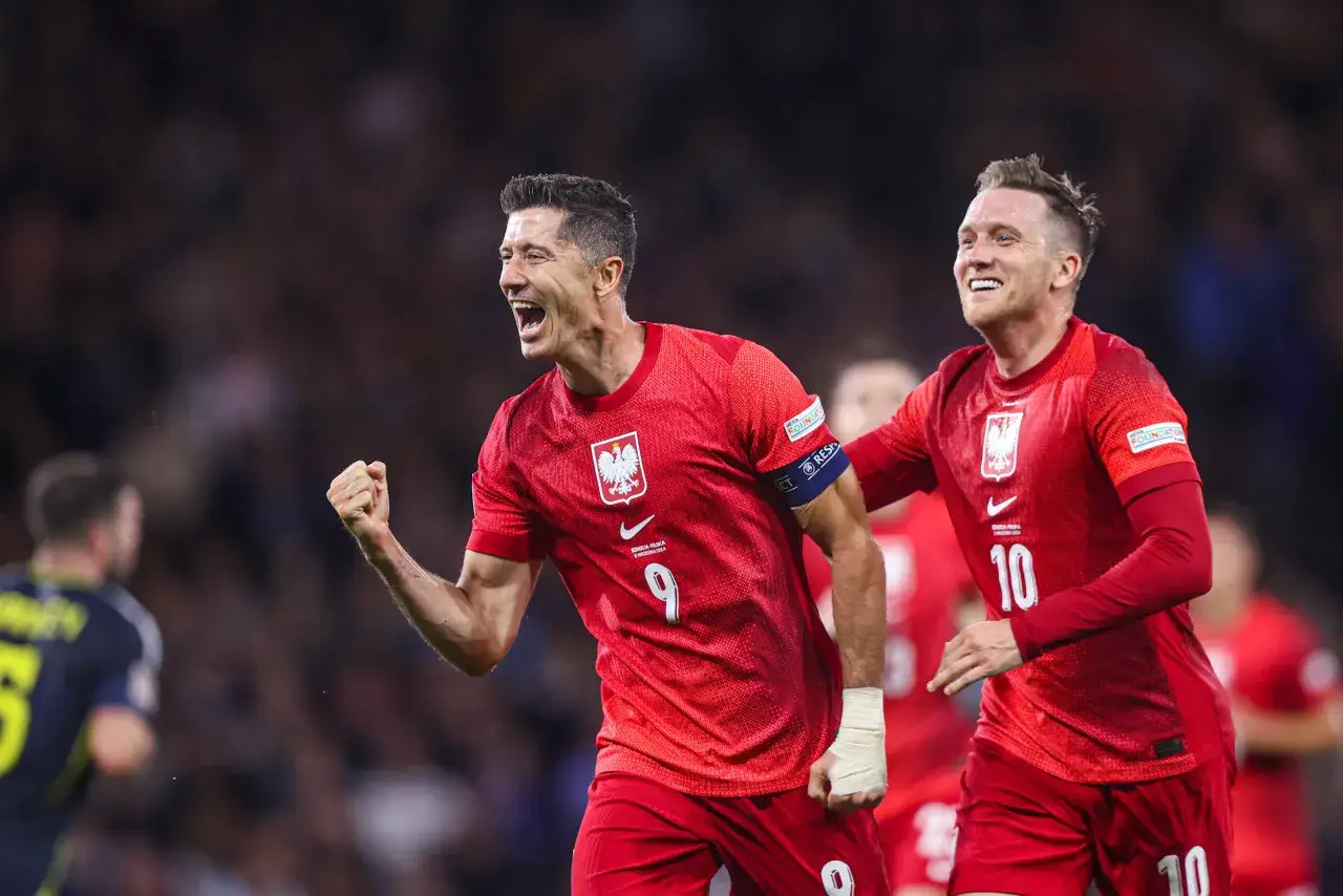 Dwóch radośnie świętujących byli piłkarze reprezentacji Polski w czerwonych strojach. Lewandowski z numerem 9 i Zieliński z numerem 10.