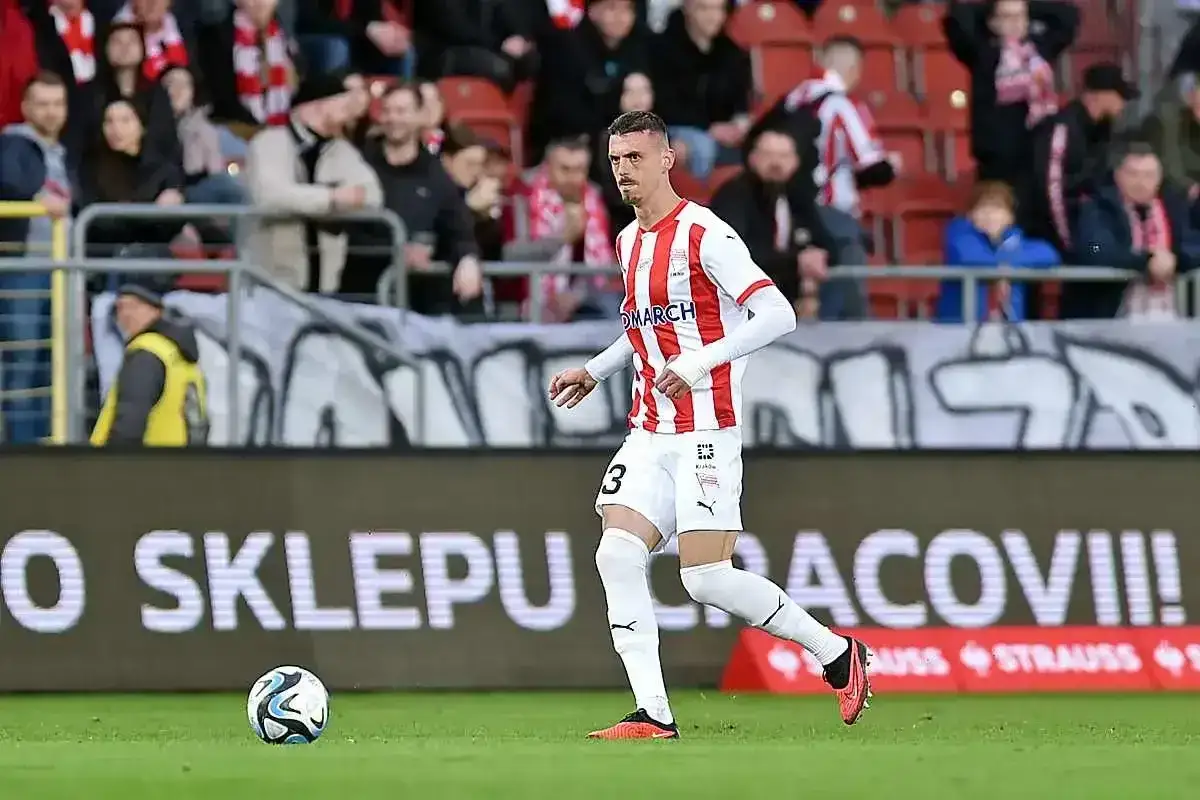 Piłkarz w białej koszulce z czerwonymi pasami, numer 3, biegnie z piłką. Mecz: Raków Częstochowa – Cracovia.