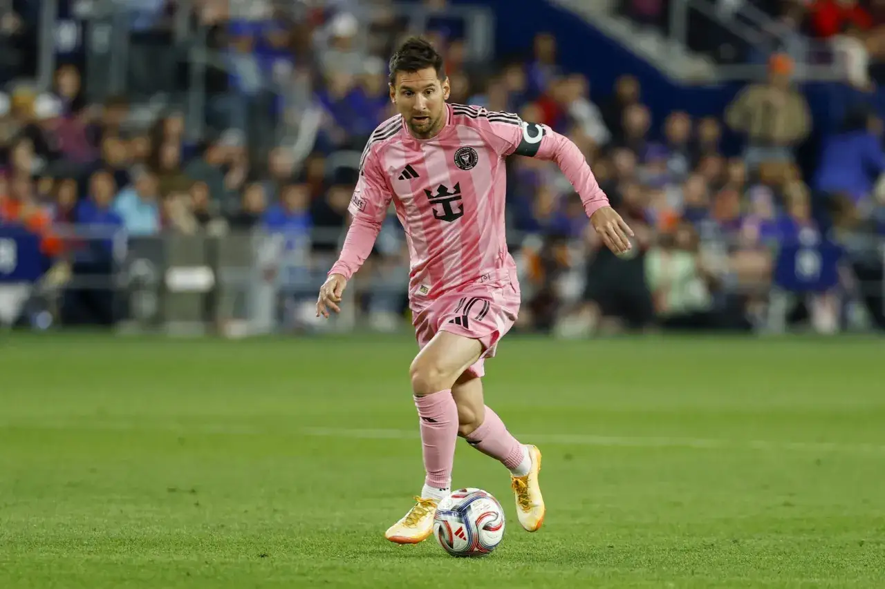 Lionel Messi w różowej koszulce Inter Miami drybluje piłką na boisku MLS.