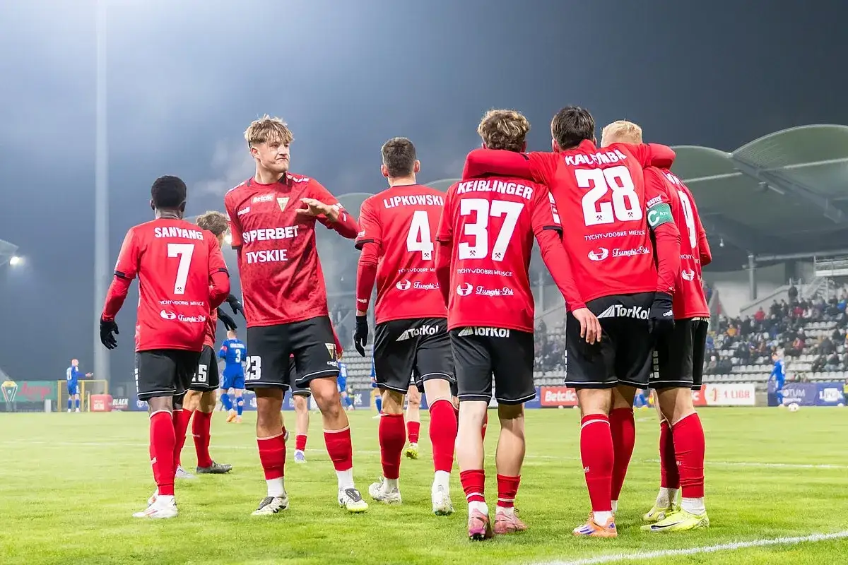 Piłkarze GKS Tychy w czerwonych strojach, z numerami 7, 4, 37, 28. Czekają na kolejne gks tychy transfery.