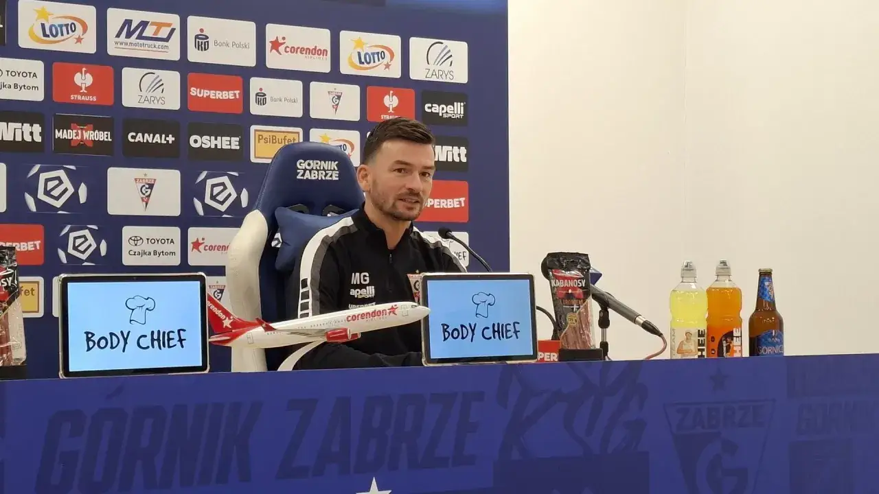 Trener Górnika Zabrze przed meczem z Rakowem Częstochowa. Na stole kabanosy i napoje.