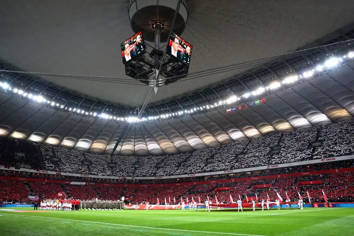 Stadion wypełniony kibicami w biało-czerwonych barwach. Na murawie trwa uroczystość przed meczem, a na telebimach widać twarze piłkarzy. To nie jest zwykły sparing, to atmosfera wielkiego wydarzenia.