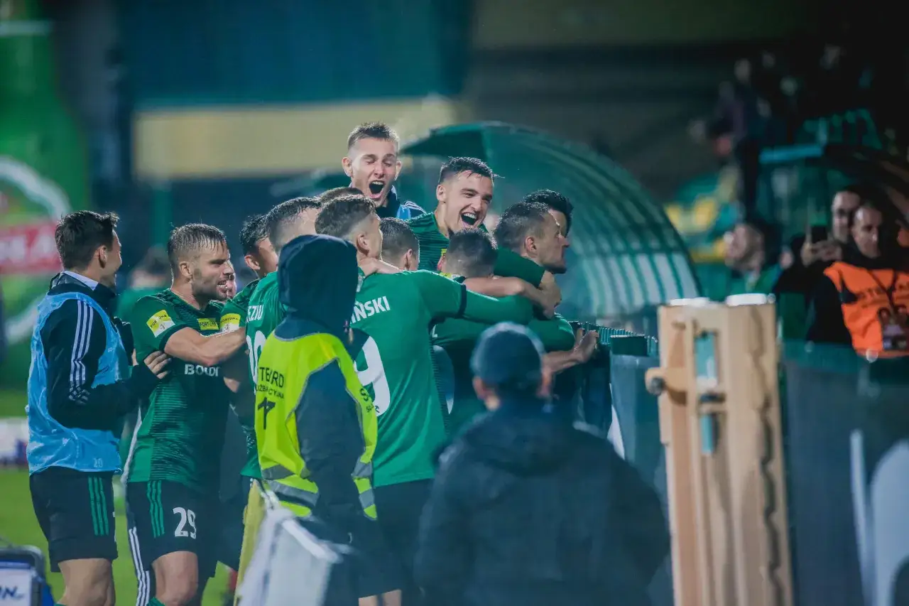 Piłkarze Górnika Łęczna świętują zwycięstwo nad GKS Tychy. Radość na twarzach zawodników, którzy wspólnie tworzą drużynę.