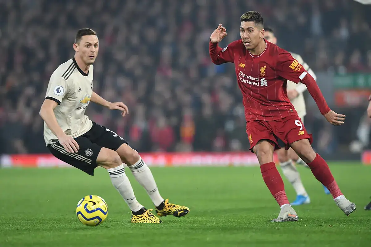 Piłkarze w akcji podczas meczu ligi angielskiej. Jeden w koszulce Manchesteru United, drugi w barwach Liverpoolu walczą o piłkę.