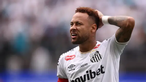 Neymar z grymasem na twarzy, trzymający się za głowę, sugeruje ból po kontuzji.