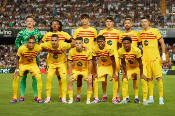 Drużyna FC Barcelona w żółtych strojach, z kapitanem na czele, pozuje do zdjęcia na tle trybun.